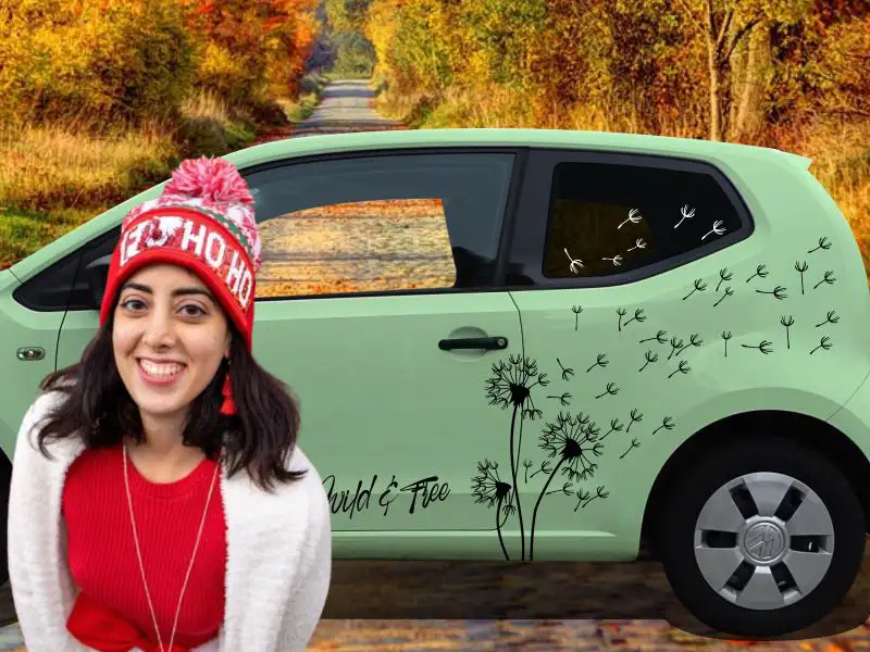 Lachende Frau vor hellgrünem VW UP mit Autoaufkleber Pusteblume in Schwarz